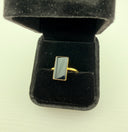 Black onyx rectangle ring with 18K gold plated brass bezel setting displayed in a black velvet jewelry box, top view.