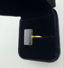 Black onyx rectangle ring with 18K gold plated brass bezel setting displayed in a black velvet jewelry box, top view.