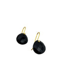 Black onyx checker cut heart drop earrings with gold hook closures laid flat on a light grey surface, showing the faceted stone detail and gold bezel setting.