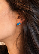 urquoise bar stud earrings with 18K gold plated brass frame displayed in a black velvet jewelry box. The earrings feature a smooth rectangular natural turquoise gemstone set between two polished gold rails.
