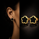 Gold and black clover shaped earrings displayed against a dark background.